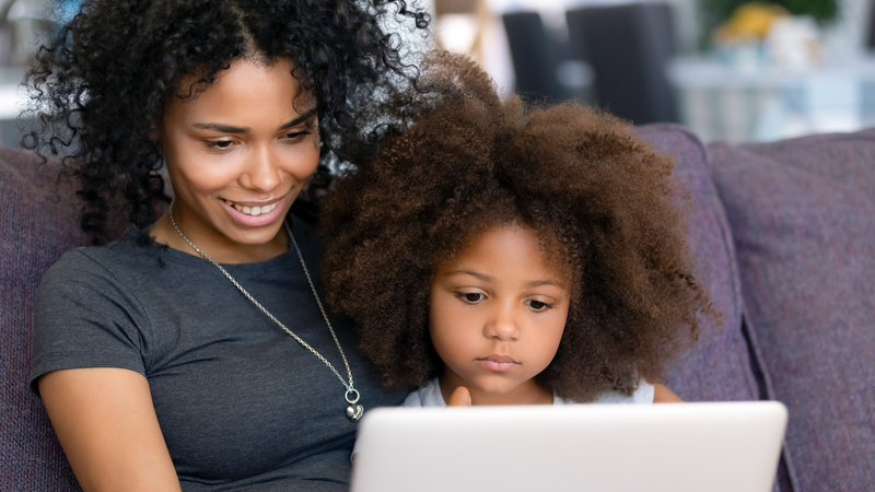 A mother and her young child talk with a healthcare professional during a telehealth appointment.