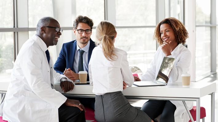 A group of medical professionals holds a meeting in a professional office.