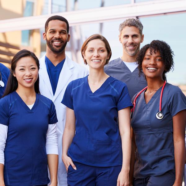 A group of medical professionals standing outside and smiling at the camera.