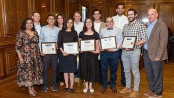 A group of faculty members from MedStar Health's Internal Medicine Residency in Washington DC stand together on a stage and hold their certificates. Everyone is wearing a mask.