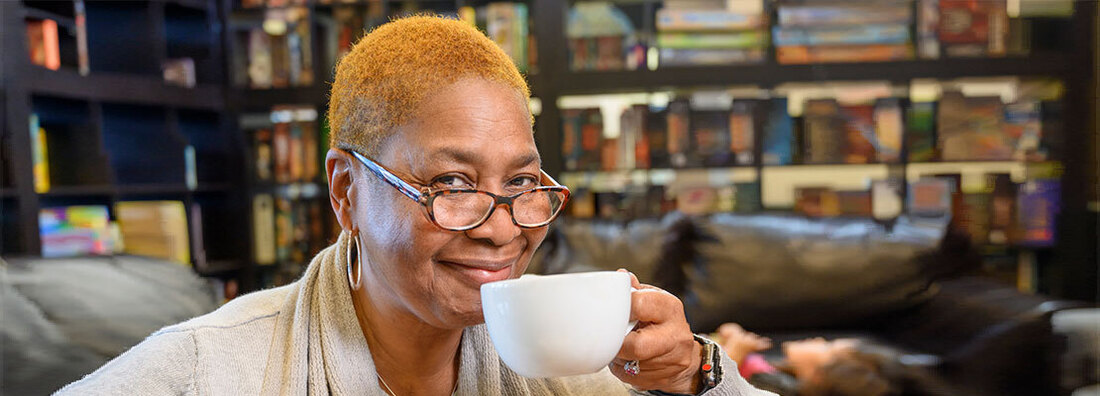 MedStar Health transplant patient Sandra Battles poses for a photo in a coffee shop. She is holding a coffee cup and smiling.