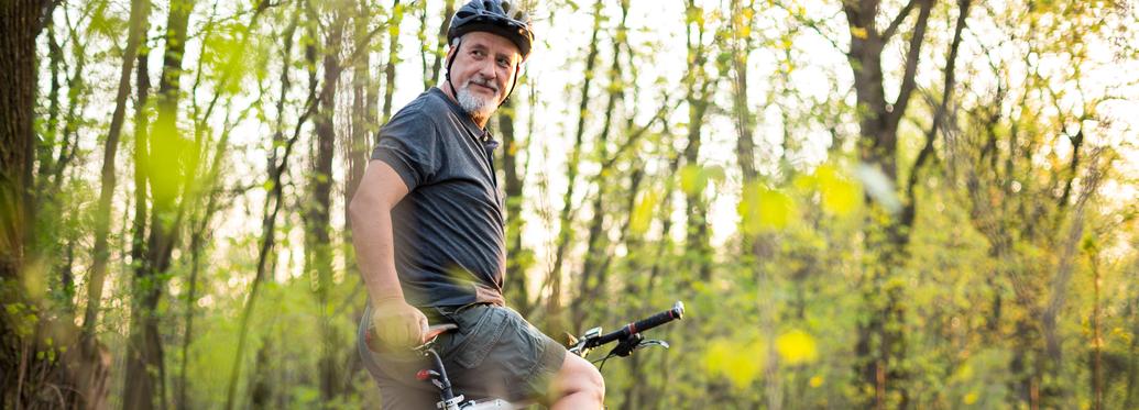 Senior man on his mountain bike outdoors in forest on a lovely summer day, staying active