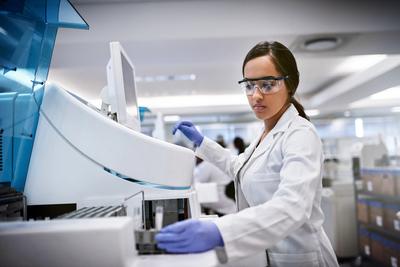 A young woman using a machine to conduct a medical test in a laboratory