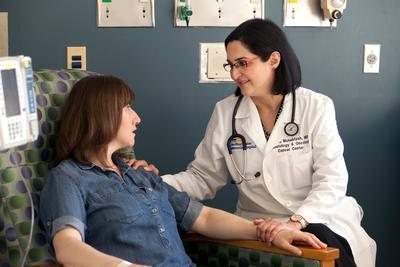 Dr Mahsa Mohebtash talks with a patient undergoing cancer treatment in a clinical setting.