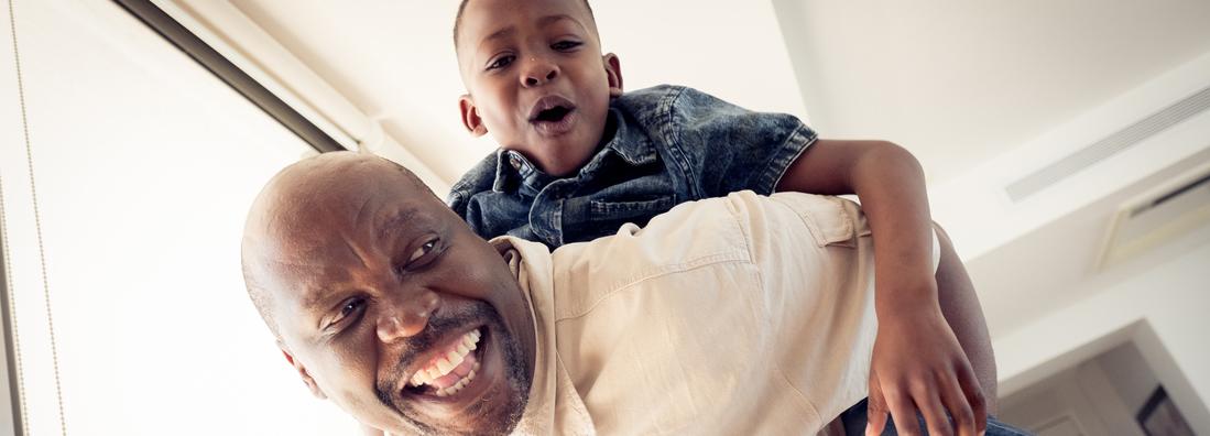 Low angle view of grandfather playing piggyback with his young grandson.