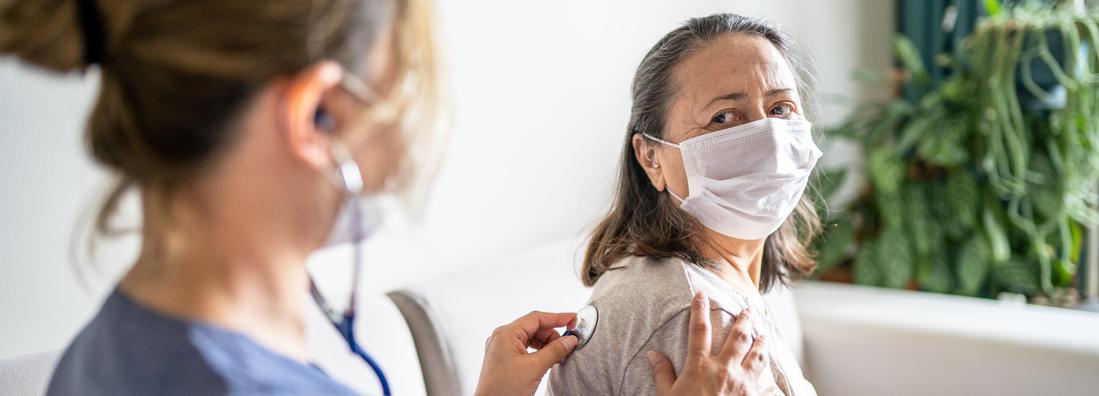 卫生世界杯欧洲区附加赛世界杯2022赛程亚洲区预选赛保健提供者拥有听诊器的一位年长的女病人听她的呼吸。女人都戴着面具。