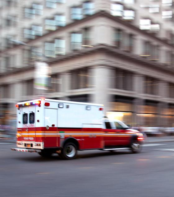 An ambulance drives through a city with lights flashing.