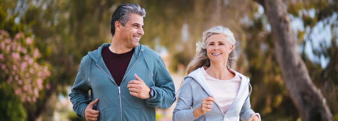 Smiling multi-ethnic senior married couple keeping active and running together on suburban street in spring