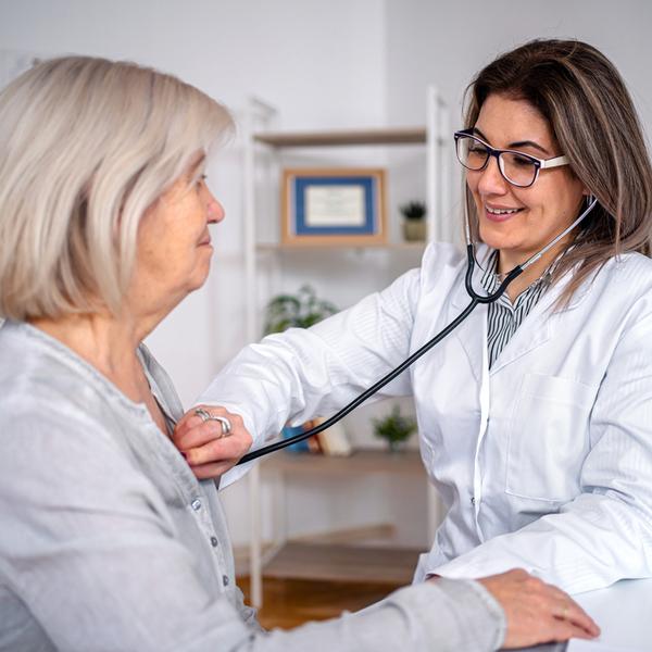 A doctor listens to the heart of a senior woman during an office visit.