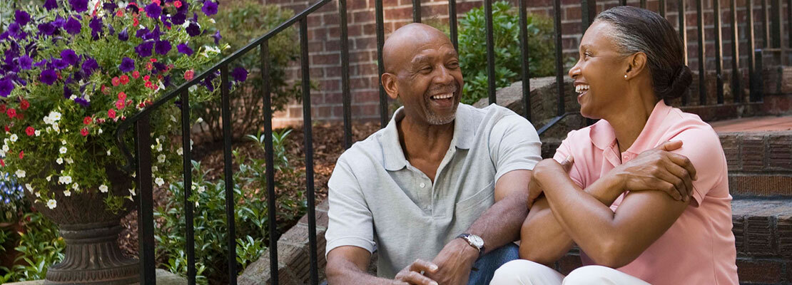 A mature african american couple talking while sitting on the front steps of their home.