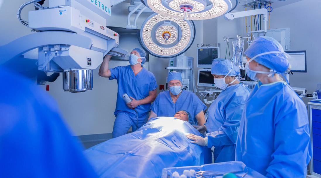 A team of masked and gowned healthcare professionals prepares to use the Mobetron interoperative radiation therapy equipment on a patient in the operating room at MedStar Georgetown University Hospital.