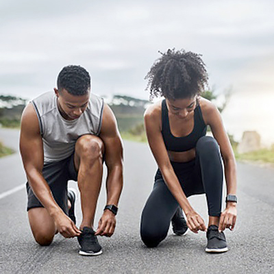 Two runners tie their shoes before a workout on a running track.