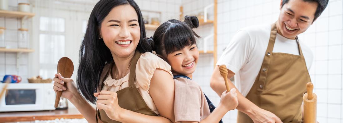 A young family laughs and has fun while cooking together in their kitchen.