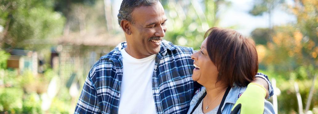 An mature african american couple walk and talk together while doing gardening work. Both people are wearing gardening gloves.