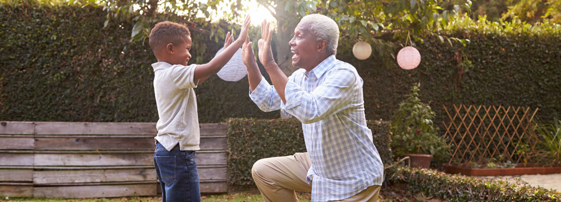 A man plays with his young grandson outdoors.