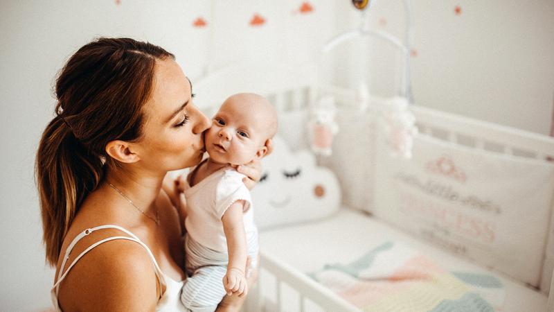 A young mother holding tenderly her newborn baby girl.