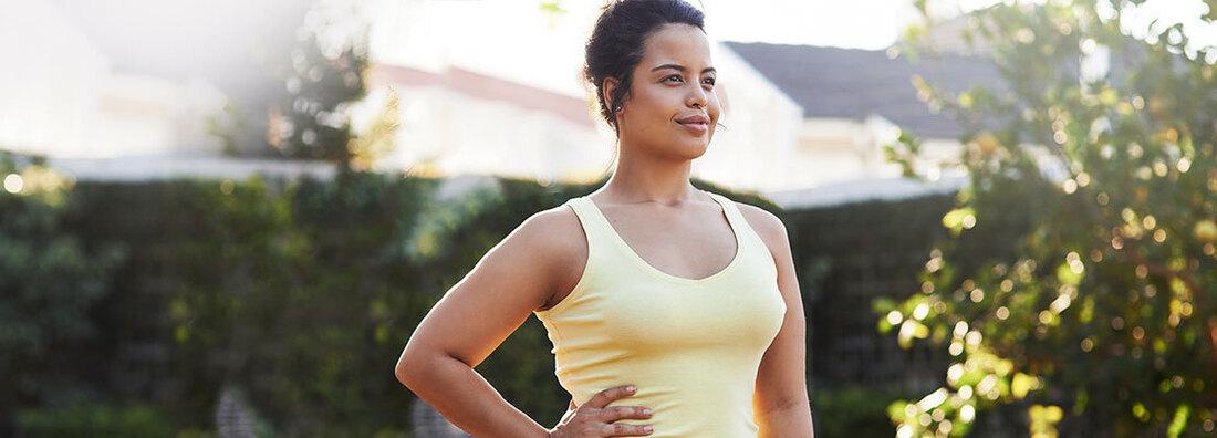 A woman stands with her hands on her hip outdoors. 