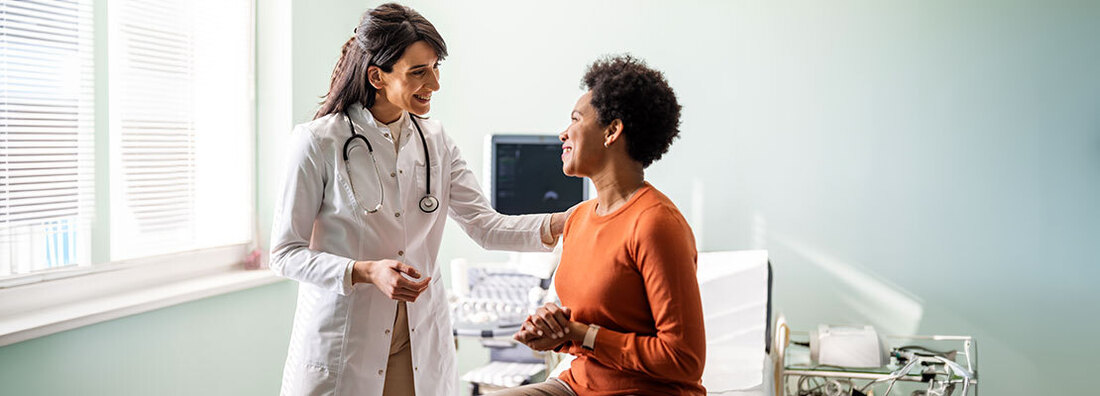 A doctor talks with a female patient during an office visit.