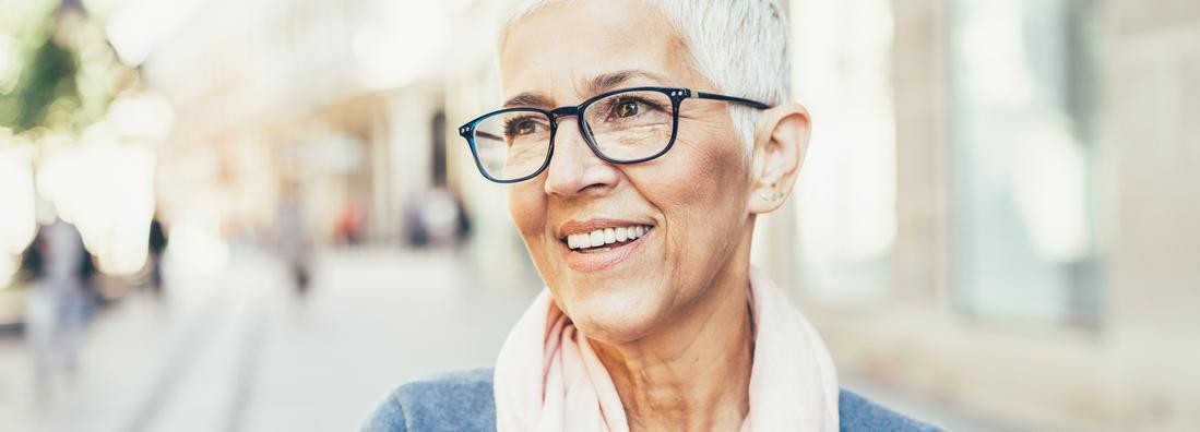 Portrait of a mature woman wearing glasses on a city street.