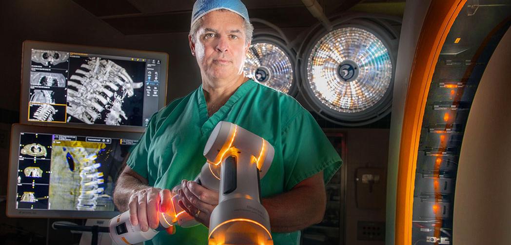 Dr Edward Aulisi stands with a Cirq robotic arm in the operating room at MedStar Washington Hospital Center.