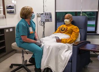 A nurse sits with a patient who is undergoing treatment in an infusion center at MedStar Health.