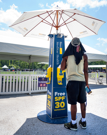 A man stands in front of a free sunscreen kiosk provided by MedStar Health.