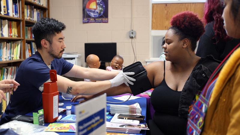 A MedStar Health associate performs a blood pressure check on a young woman at a community health event at MedStar Southern Maryland Hospital Center.
