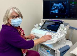 Dr Melissa Fries poses for a photo in front of an ultrasound machine.