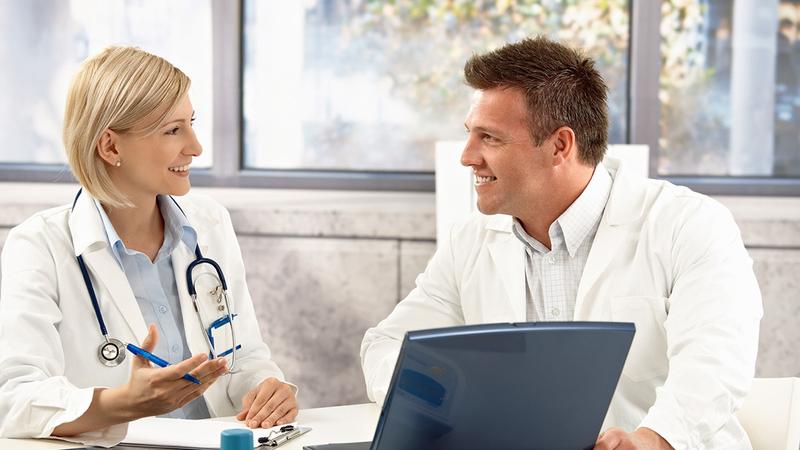 Two doctors talk while sitting in an office.