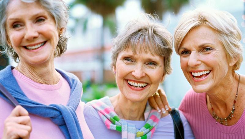 Three mature women smile for the camera.