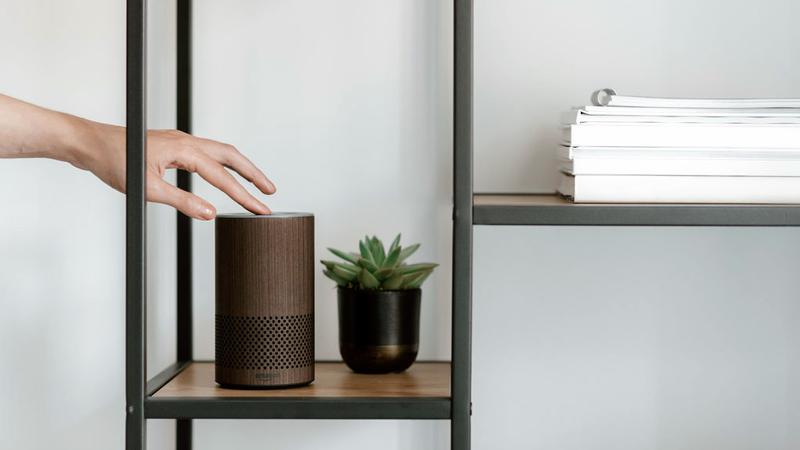 Close up of a hand touching an Amazon Alexa device.