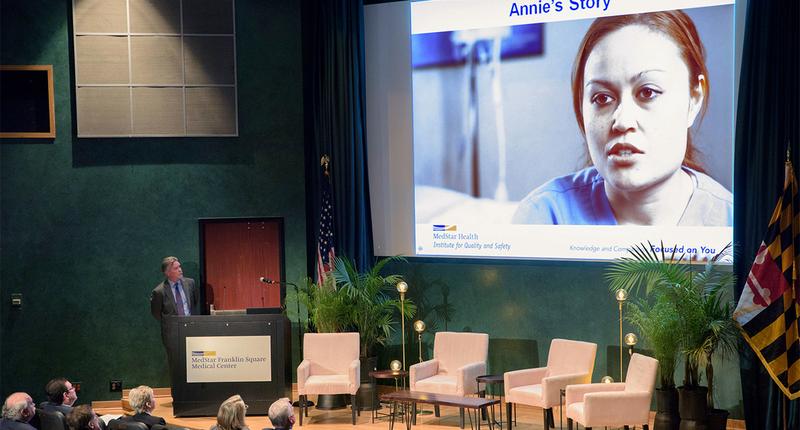 David Mayer stands behind a podium during a conference about patient safety.