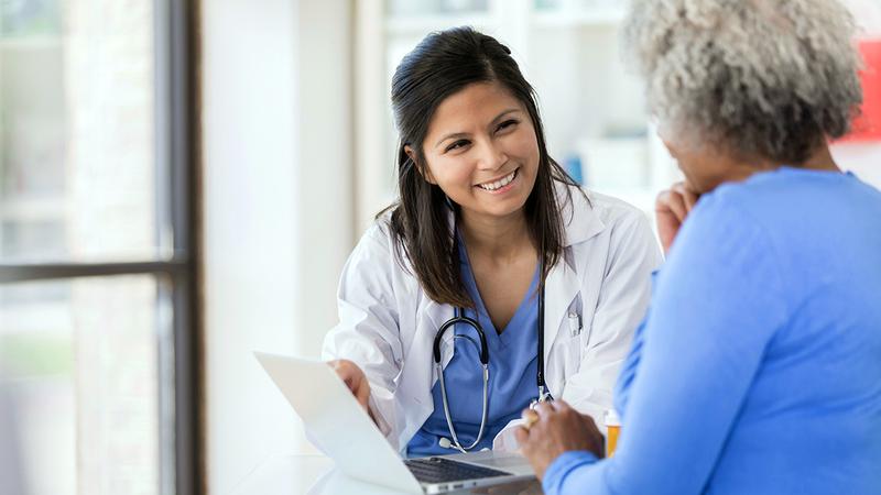 A doctor talks with a patient in the lobby of a hospital.