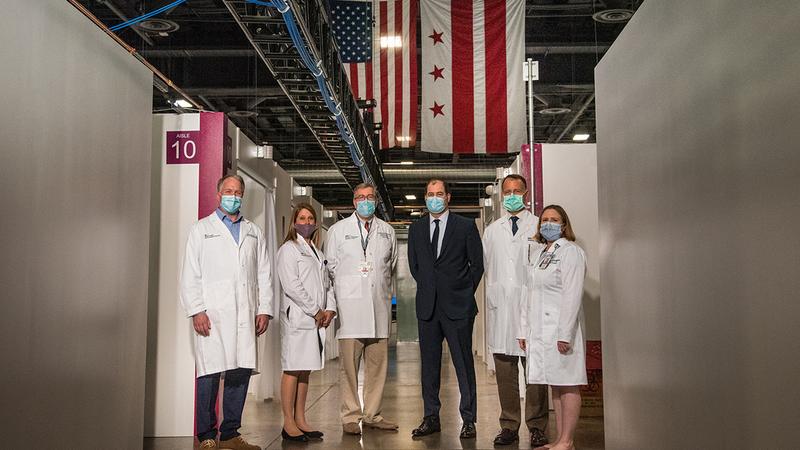 Doctors in white lab coats wearing masks pose inside the COVID-19 field hosptial set up at Washington DC's convention center.