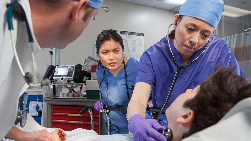 Doctors and nurses tend to a sick patient in a hospital emergency department.