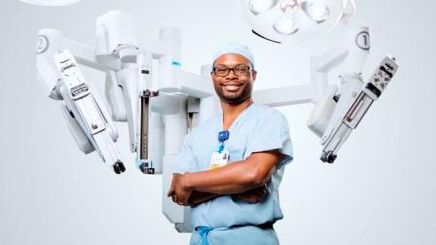 Michael Gillespie stands in front of a robotic surgery system.