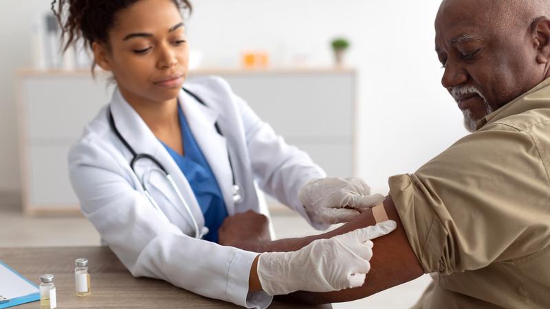 A healthcare professional gives a man a seasonal vaccine in a clinical setting.