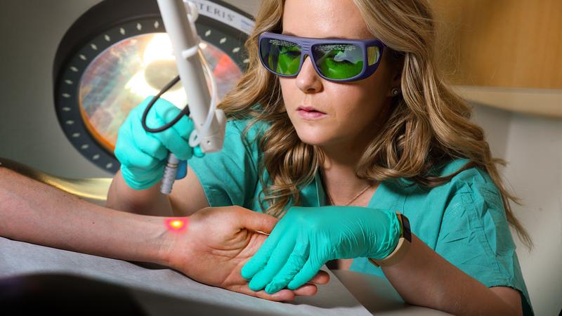 在MedStar华盛顿医院中心，Taryn Travis医生在病人手臂上演示激光治疗设备的使用。
