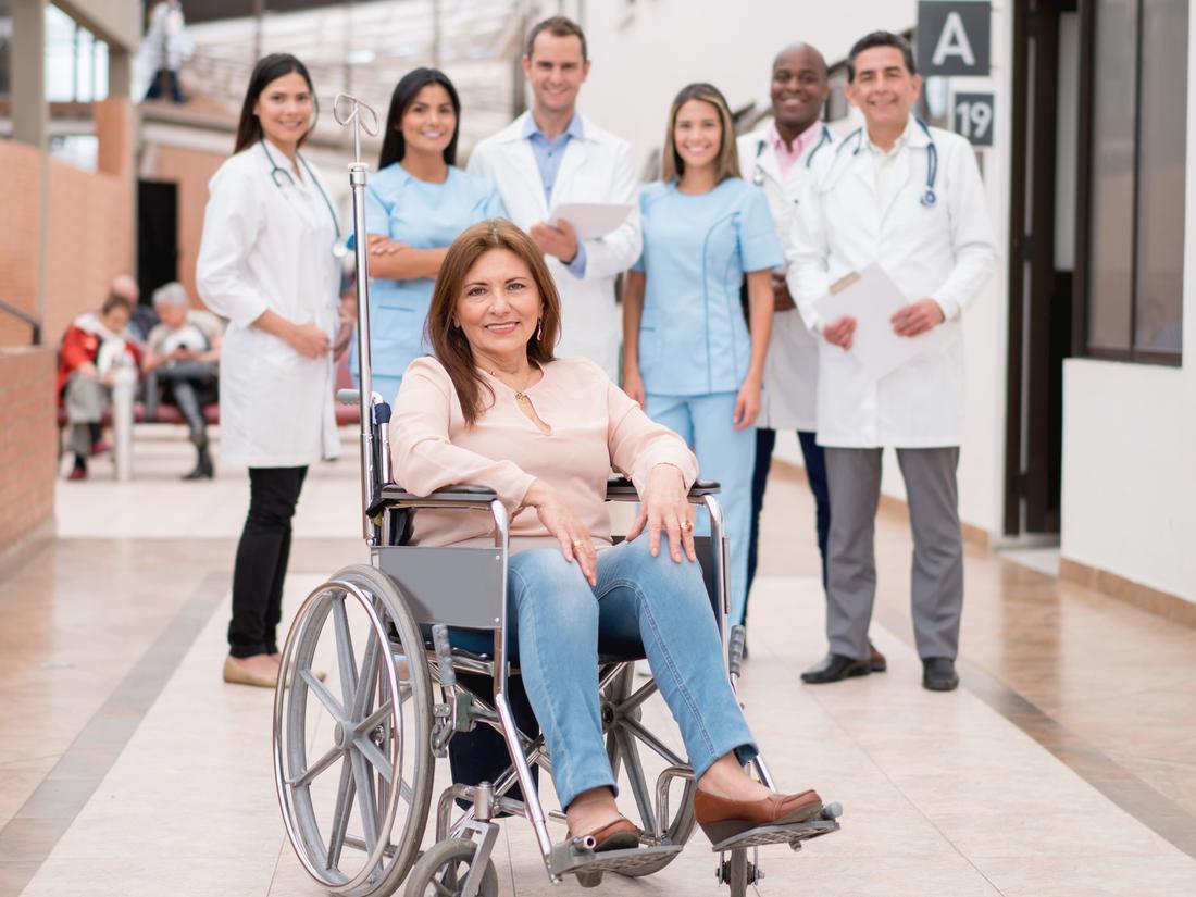 女病人坐在轮椅上，后面站着一组医生。
