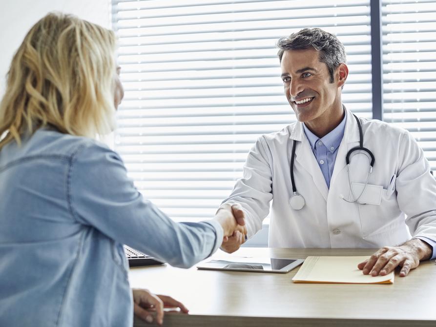 Doctor shaking hands with woman in a medical office.