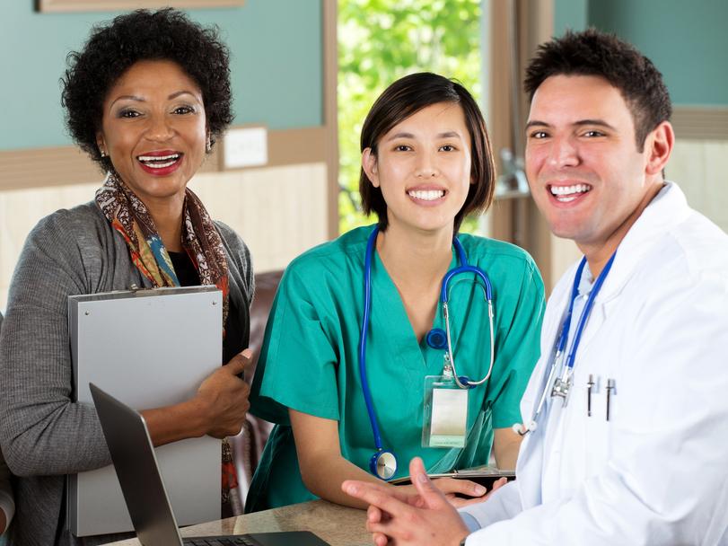 Workers in a medical office smiling and looking at the camera.