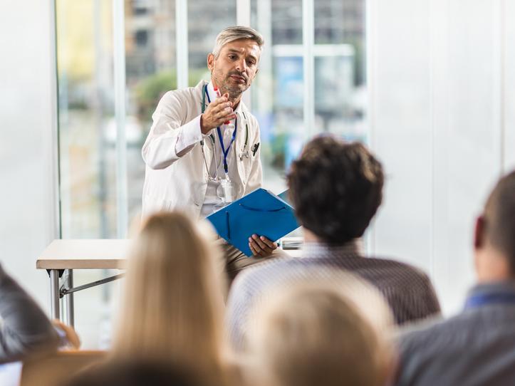 Male doctor teaching a seminar to students in a board room