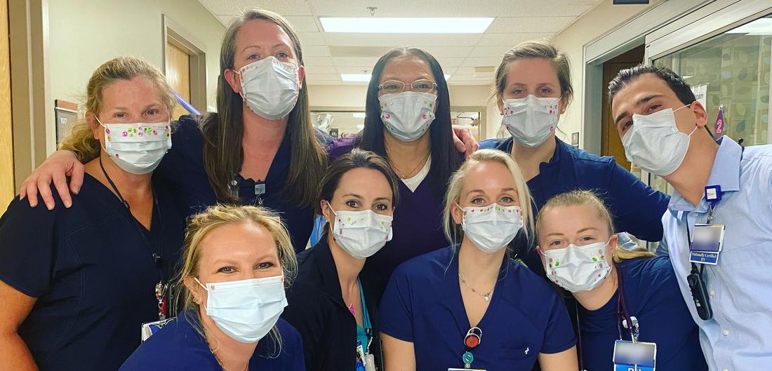 A team of nurses poses for a photo inside of MedStar Montgomery Medical Center. All of the people are wearing masks.