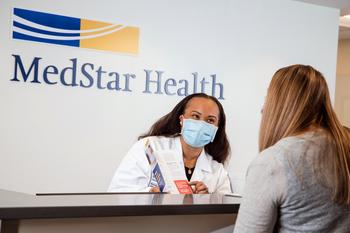 A MedStar Health associate talks with a patient at the reception desk of a doctor's office.