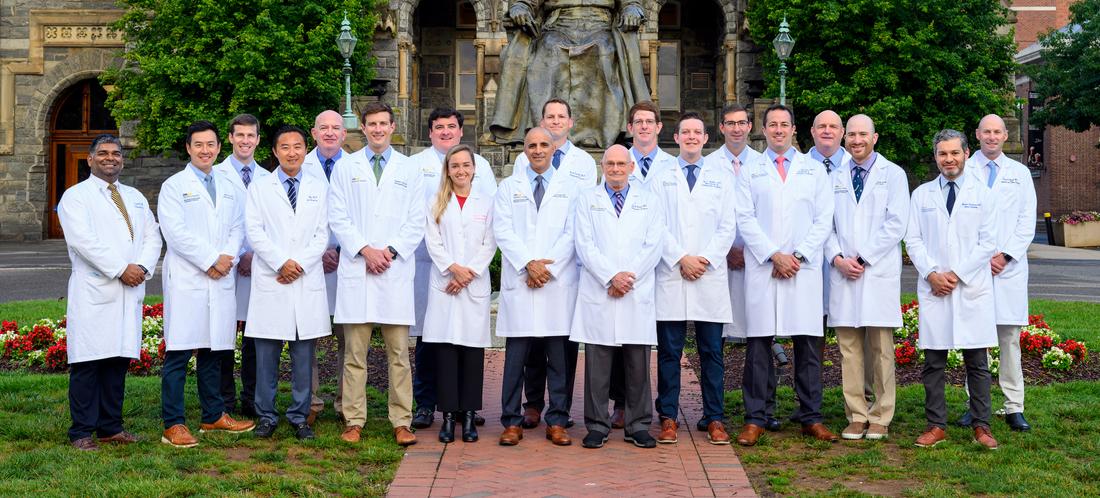 华盛顿特区，一群刚毕业的MedStar健康整形外科住院医生在乔治敦大学校园里一座巨大的石头建筑前站着，对着镜头摆姿势。所有人都穿着白大褂。