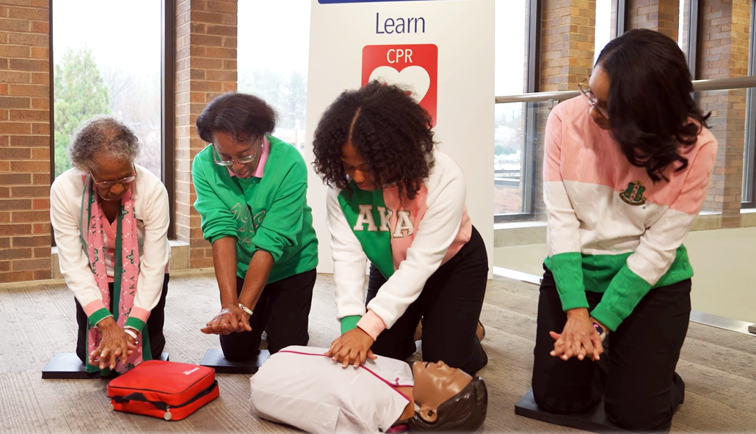 Members of Alpha Kappa Alpha sorority learn CPR on a simulation mannequin during filming of MedStar Health's CPR training video.