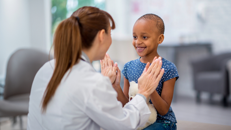 A doctor talks with a pediatric cancer patient.
