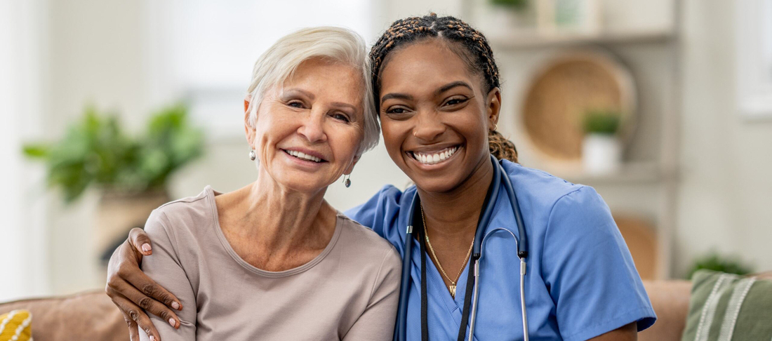 A female medical professional comforts a female patient who is wearing a head scarf.