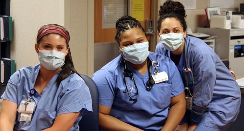 三名来自MedStar圣玛丽医院的护士戴着口罩在护士站合影。