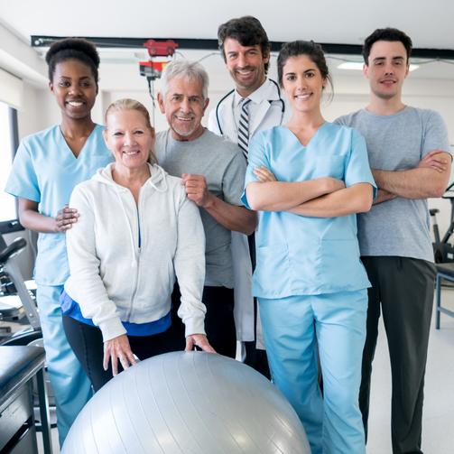 A team of physical therapists pose for a photo in a rehabilitation gym.